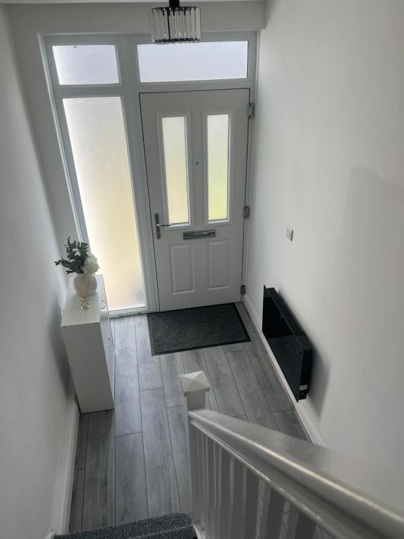 雷纳姆Luxury 3 bedroom house Rainham Essex - Free parking and Wifi的一条带白色门的走廊和一个带楼梯的楼梯