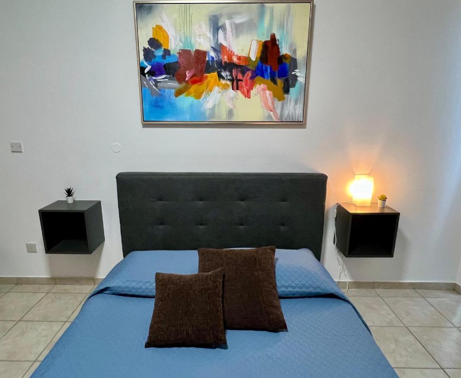 LivadhiaFatCow Seaside Suites的卧室配有蓝色的床和墙上的绘画作品