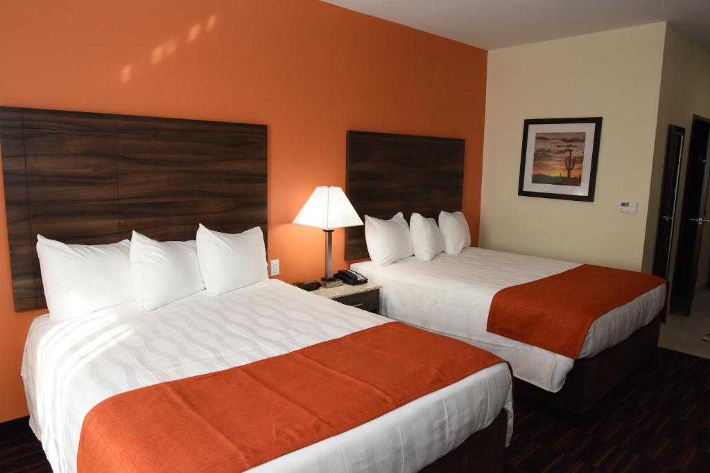 EnidHome Away Kitchen Suites Enid的橙色墙壁的酒店客房内的两张床