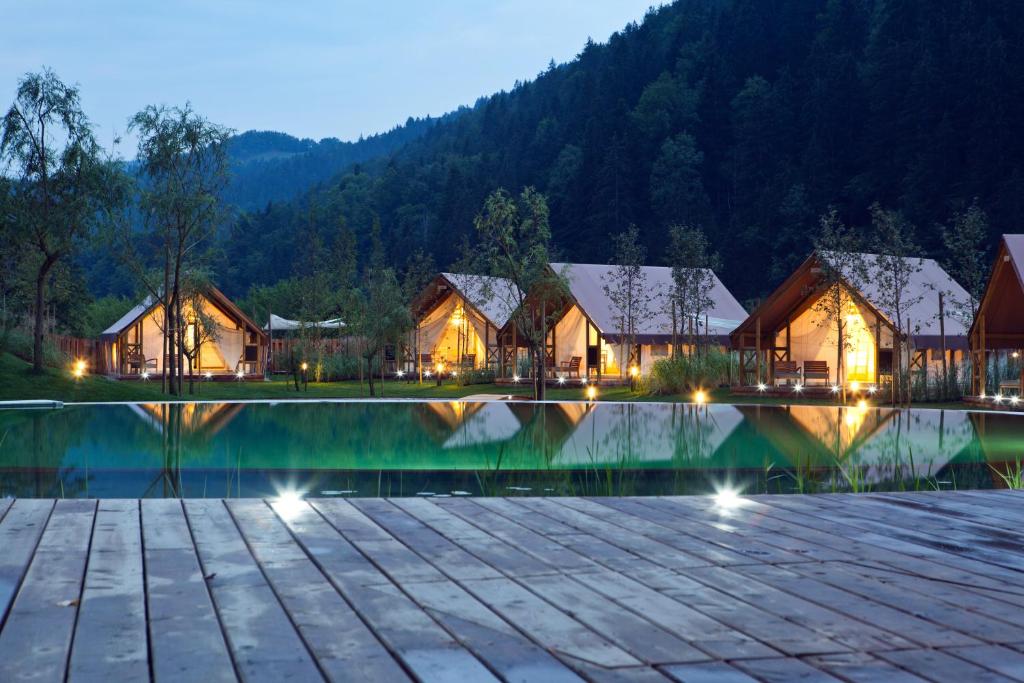 LjubnoCharming Slovenia - Herbal Glamping Resort Ljubno的夜间带游泳池的度假村