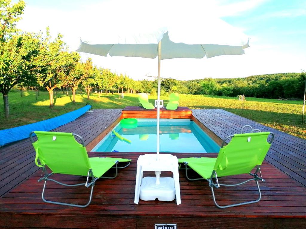 Velika RemetaSunny Side Fruska Gora的一个带游泳池、两把椅子和遮阳伞的甲板
