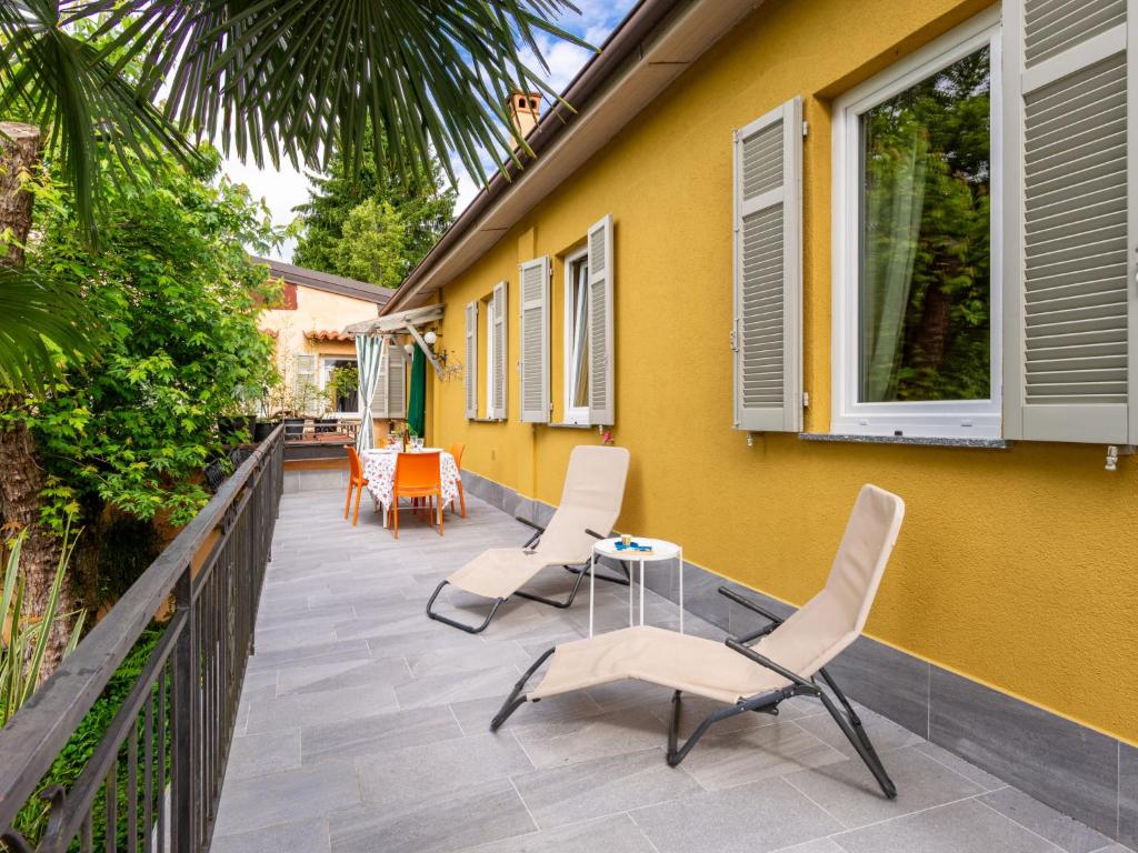 Invorio InferioreHoliday Home Atelier-1 by Interhome的一座黄色的房子,庭院里设有椅子和桌子
