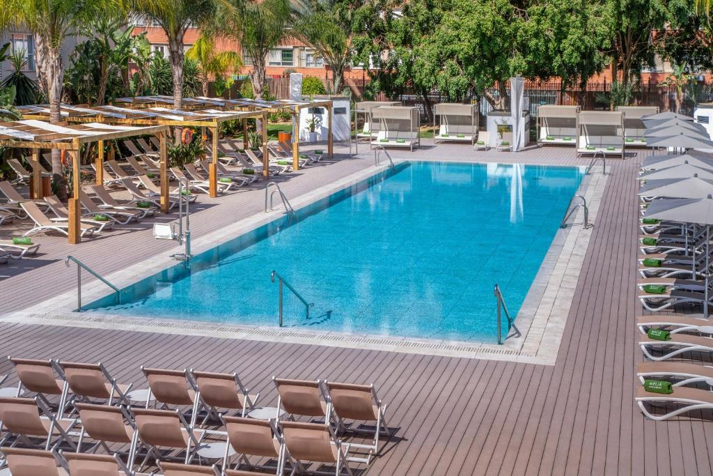 塞维利亚布雷罗斯美利亚酒店的一个带桌椅的大型游泳池