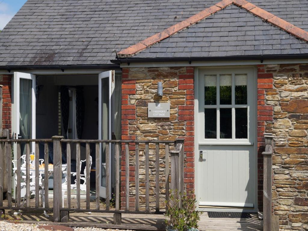 达特茅斯1 Keepers Cottage, Hillfield Village的砖屋,有白色的门和栅栏
