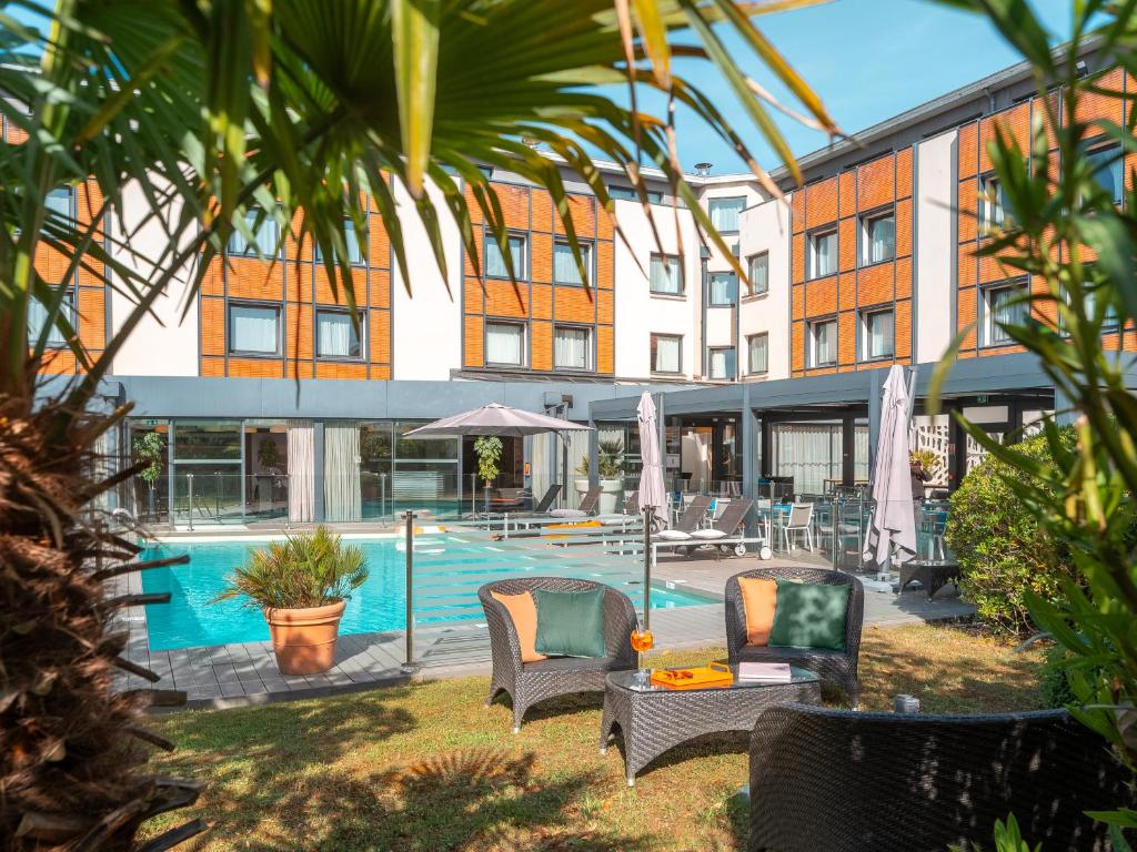 布拉尼亚克图卢兹机场智选假日酒店的一座带游泳池和椅子的酒店和一座建筑