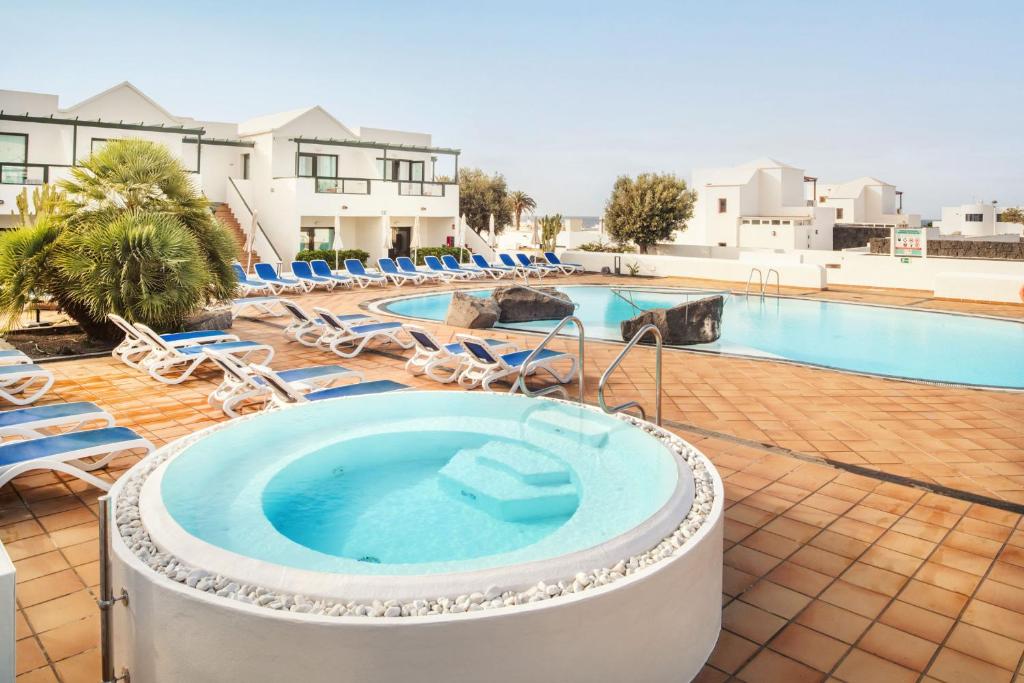 卡门港Hotel Pocillos Playa, solo Adultos的一个带热水浴缸和躺椅的游泳池
