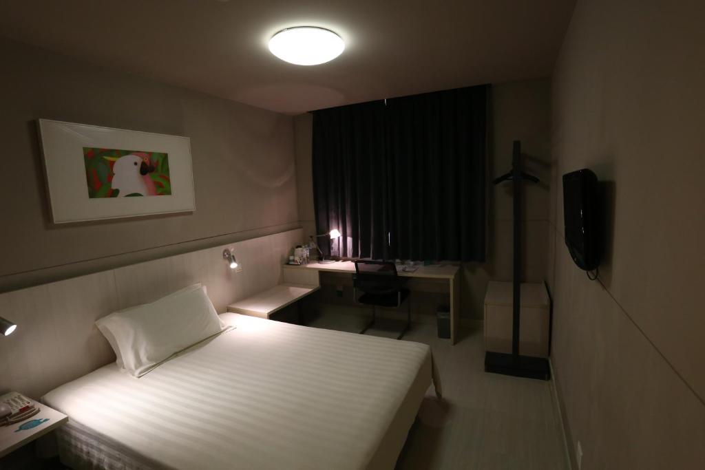 无锡锦江之星无锡梅村酒店的一间卧室配有一张床、一张书桌和一个窗户。