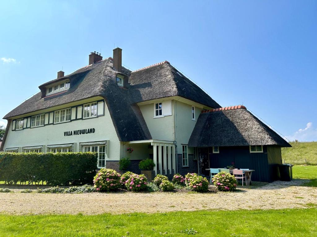 登乌弗Villa Nieuwland B&B的一座带茅草屋顶的大型白色房屋