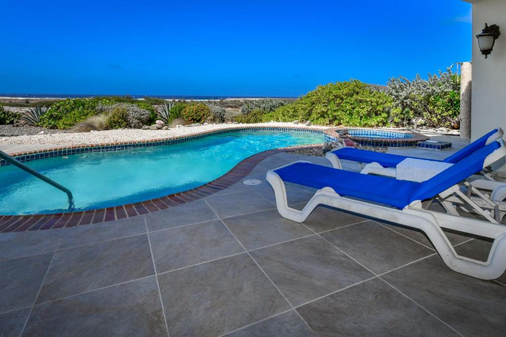 棕榈滩火太阳海岸高尔夫度假酒店的游泳池配有2把躺椅和电视