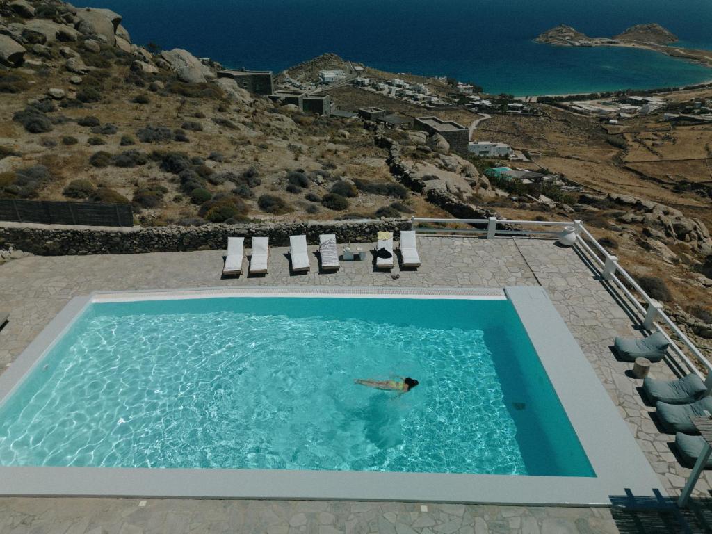 卡拉法蒂斯Mykonos Supreme Comfort Suites & Villas的在海景游泳池游泳的人