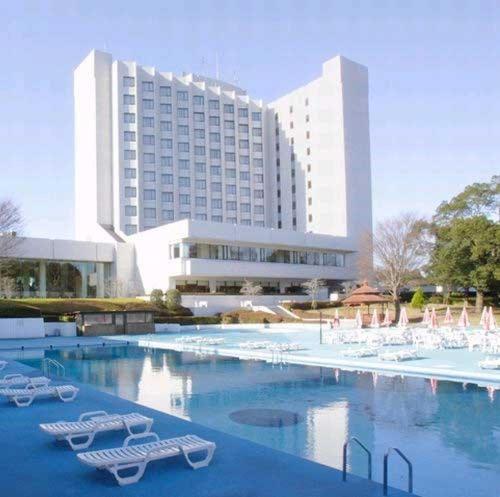 成田International Resort Hotel Yurakujo的一座大楼前的游泳池,配有躺椅