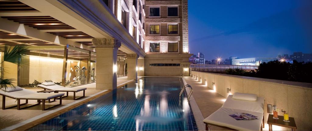 台北美丽信花园酒店的酒店游泳池设有椅子,酒店大楼