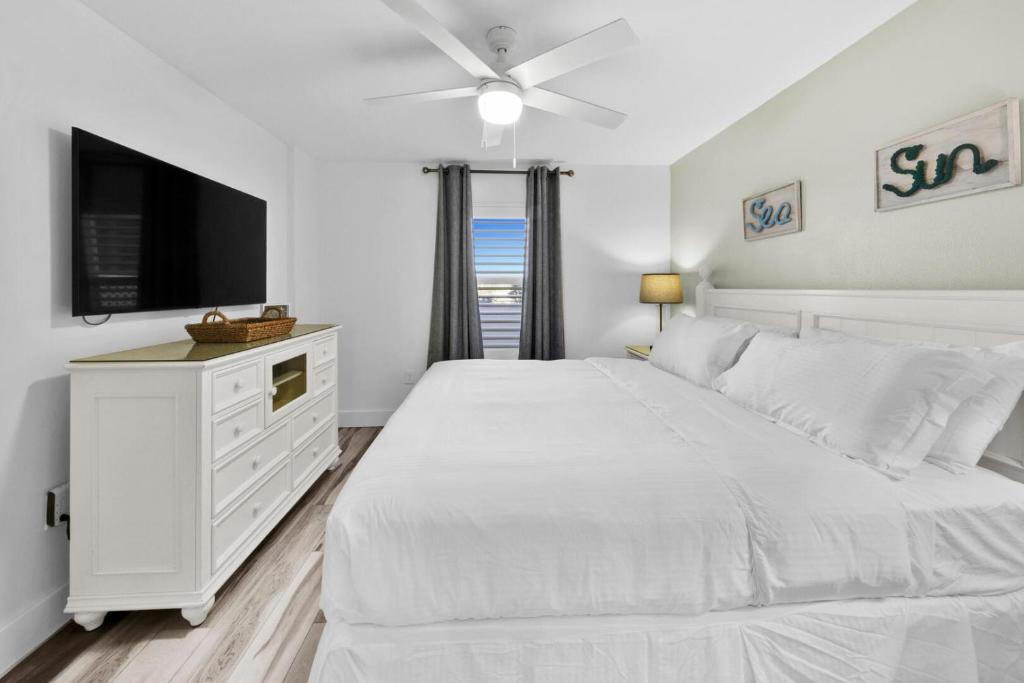 德斯坦Beautiful Updated Pelican Beach Unit!!!的白色卧室配有白色的床和平面电视