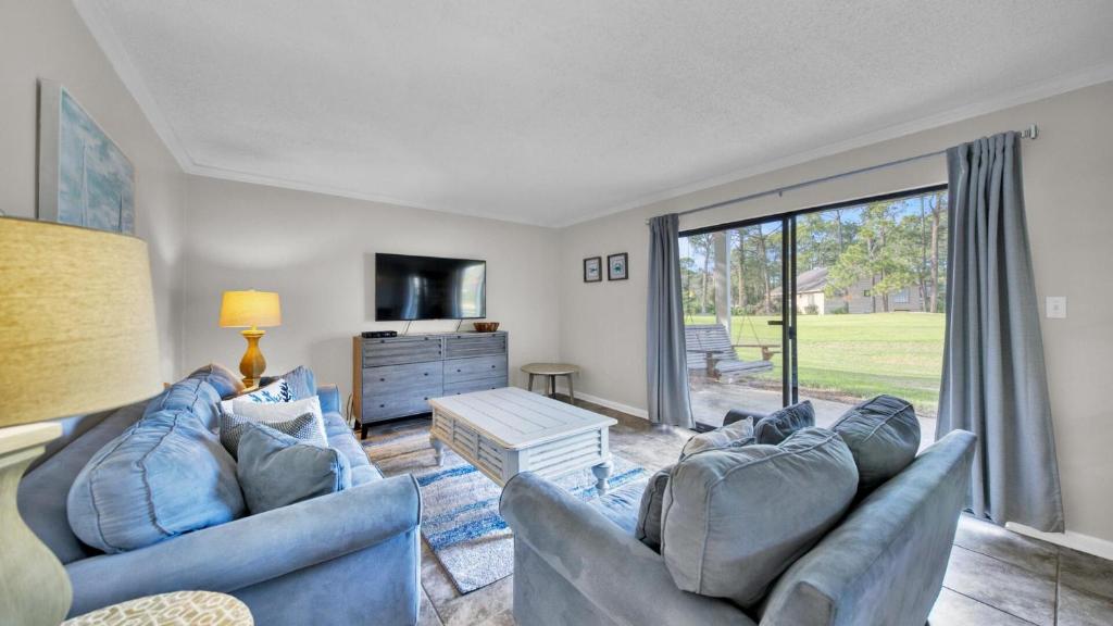 德斯坦Cozy renovated ground floor unit - Golf Villa - on the Golf Course的客厅设有2张蓝色的沙发和大窗户