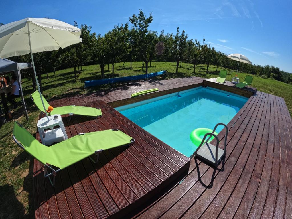 Velika RemetaSunny Side Fruska Gora -touristic estate的木制甲板上的游泳池,配有两把椅子和一把遮阳伞