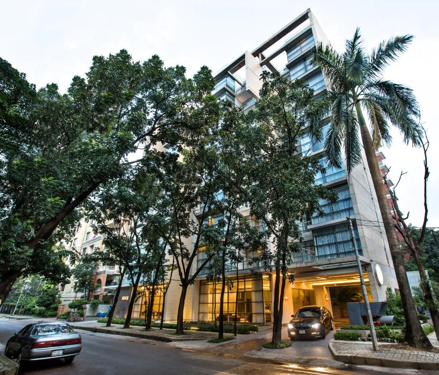 达卡太空公寓式酒店的街道前方有棕榈树的建筑