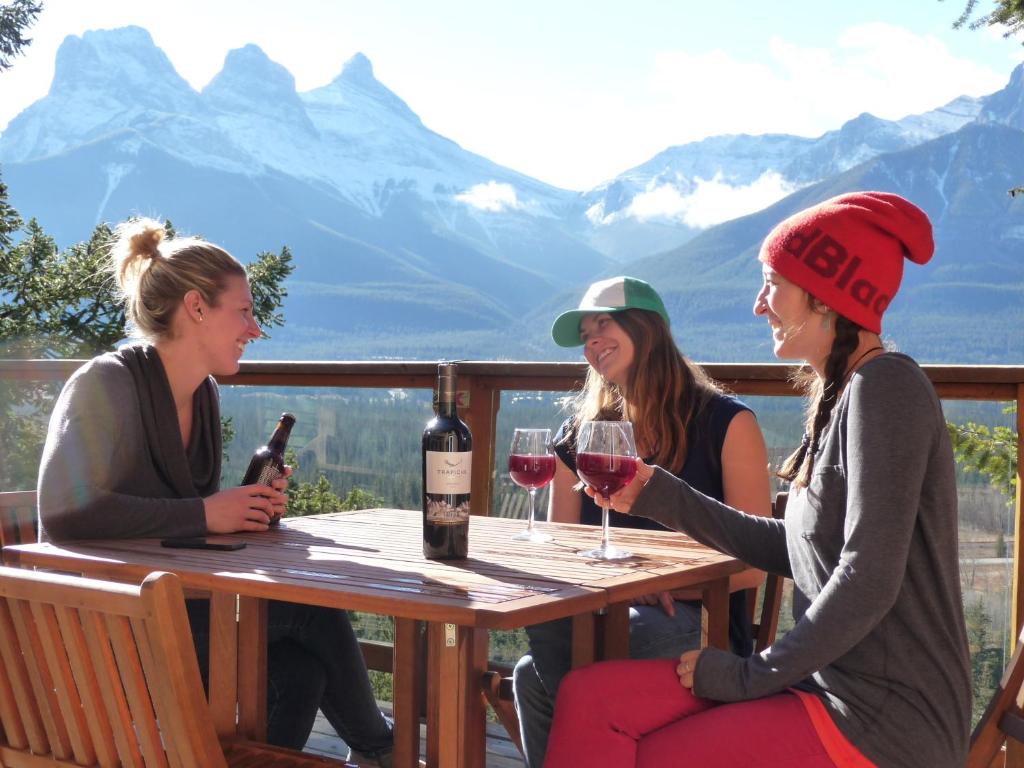 坎莫尔Canmore Alpine Hostel - Alpine Club of Canada的三个女人坐在桌子上,戴着酒杯
