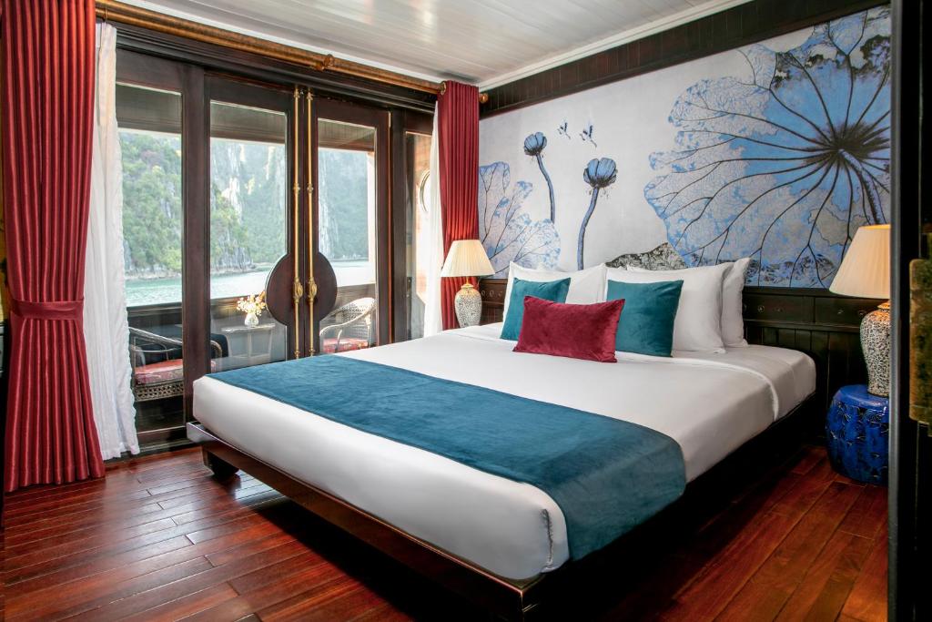 下龙湾传奇下龙私人邮轮酒店 - 哈亚巡游管理局的一间卧室配有一张带蓝色和红色枕头的大床