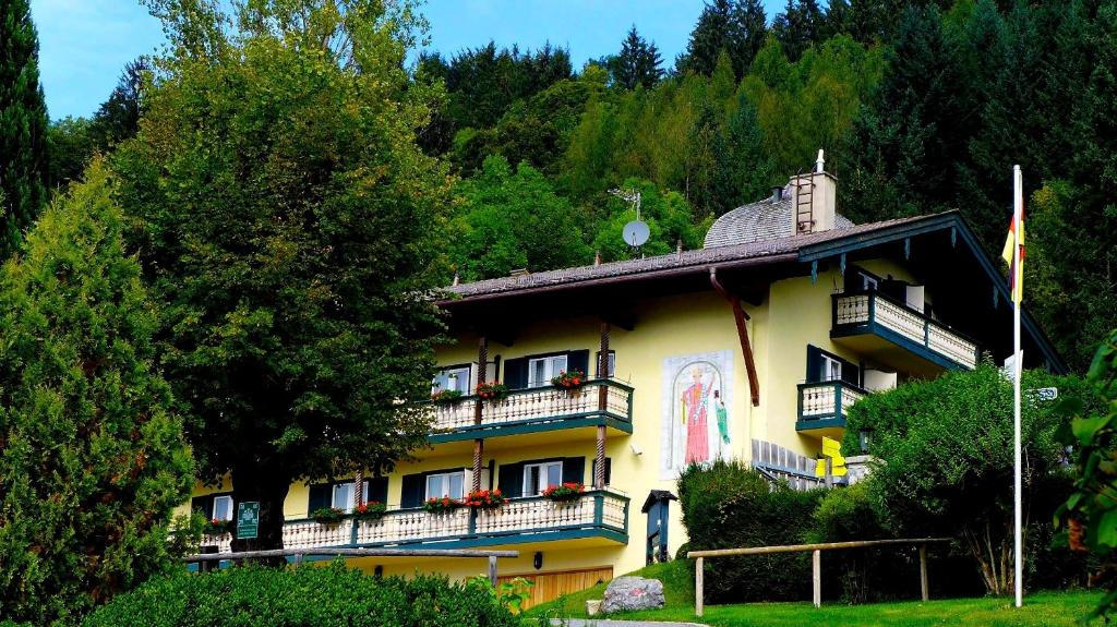 泰根塞韦斯特霍夫山屋酒店的一座带阳台和树木的大型黄色建筑