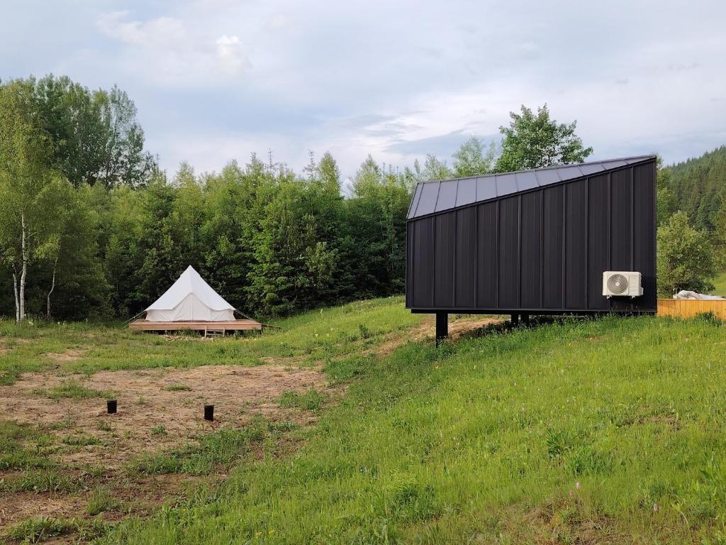 BorcaSabasa Forest Retreat的田野上的黑色建筑,有帐篷