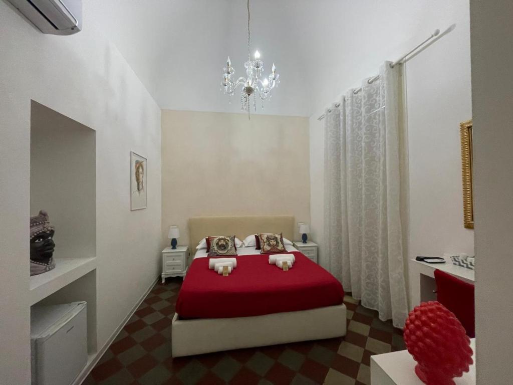 卡塔尼亚Sleep Inn Catania rooms - Affittacamere的一间卧室配有一张红色的床和吊灯。