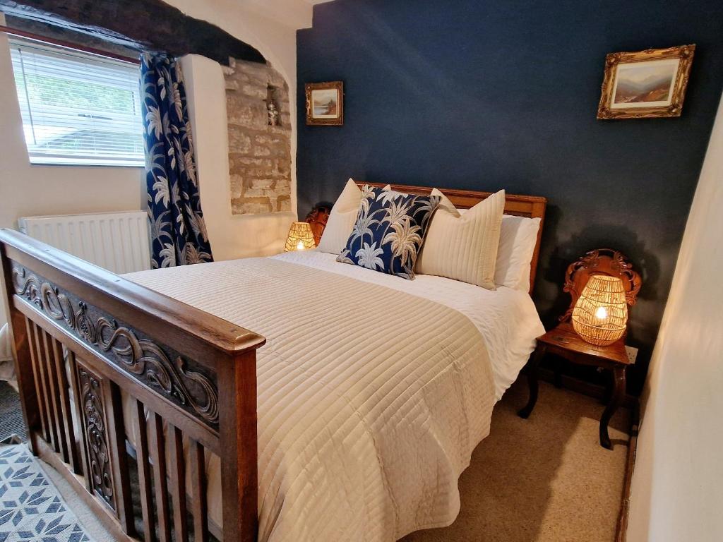 霍姆弗斯THE OLD WASH KITCHEN - Charming Character Cottage in Holmfirth, Yorkshire的一间卧室配有一张带蓝色墙壁的大床