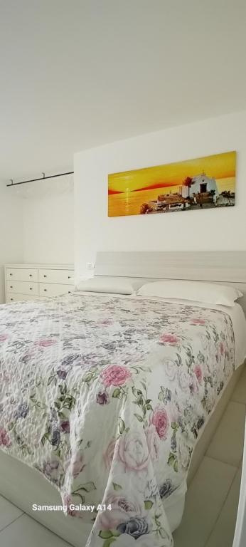 伊斯基亚Marintò Apartaments的白色卧室配有带花卉毯子的床