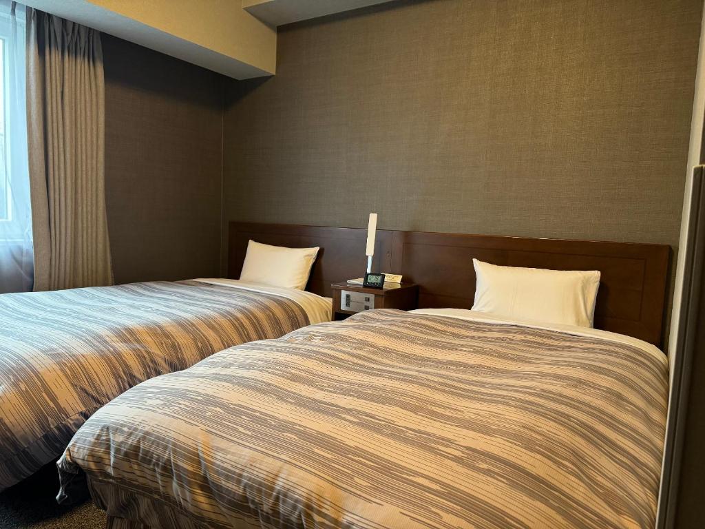 土岐市土岐市路线酒店的两间相邻的床铺位于酒店客房内