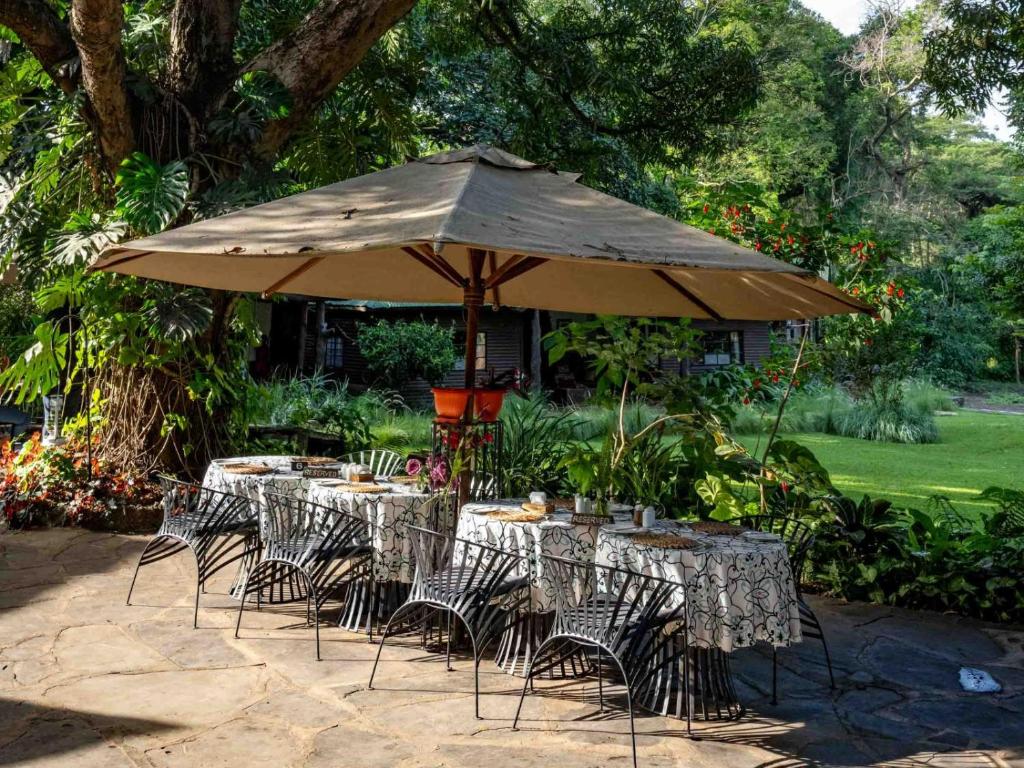 阿鲁沙Mount Meru Game Lodge & Sanctuary的一组桌子和椅子,放在伞下