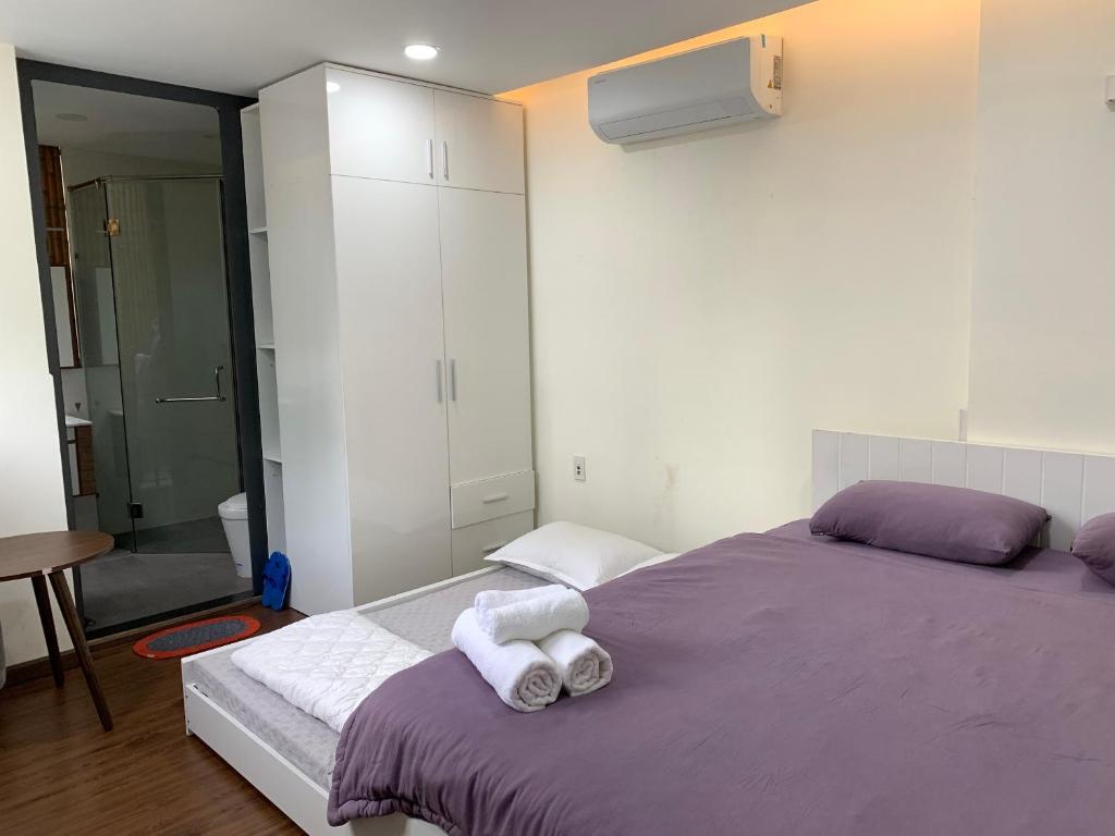 胡志明市LUCY HOTEL & APARTMENT的一间卧室配有一张紫色床和毛巾