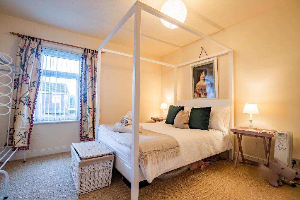 赫里福德Guest Homes - Over the Bridge Cottage的一间卧室设有天蓬床和窗户。