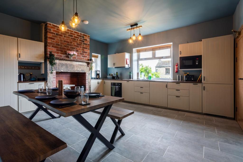 Clayton WestHolmfield House的厨房配有木桌和壁炉。