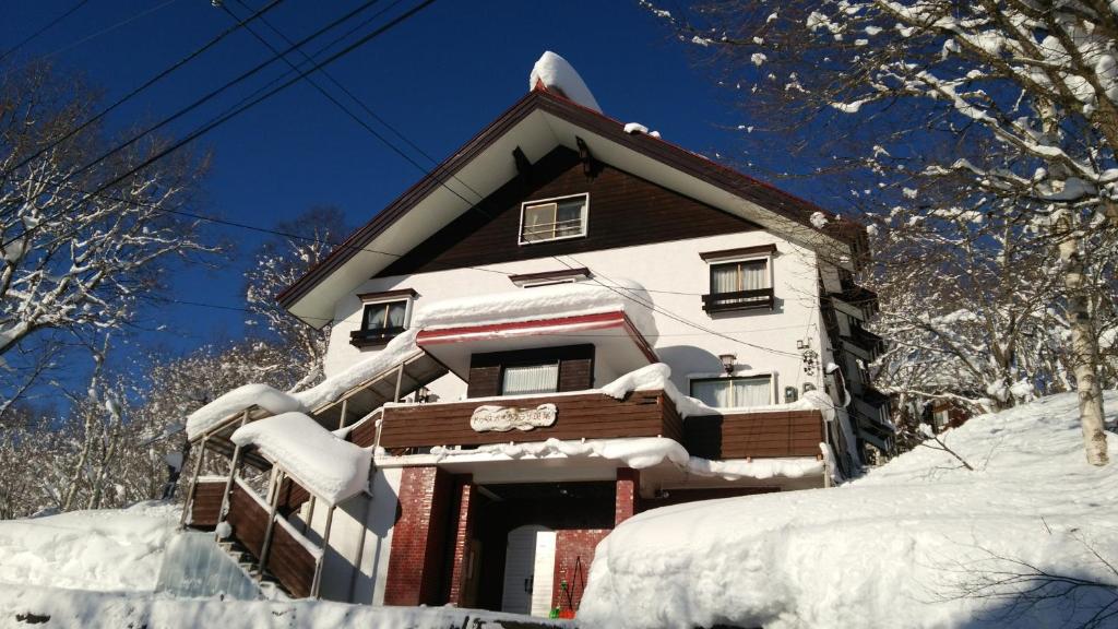 饭山市斑尾运动旅馆的雪覆盖在雪覆盖的树上的房子