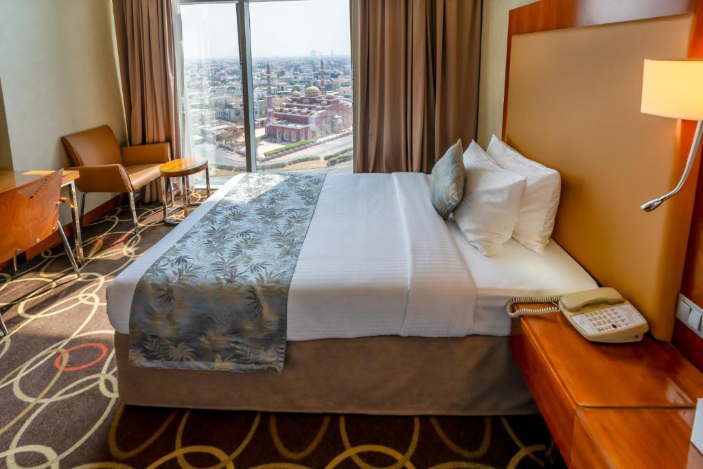 迪拜Montreal Barsha Hotel的酒店客房设有一张带电话的床和窗户。