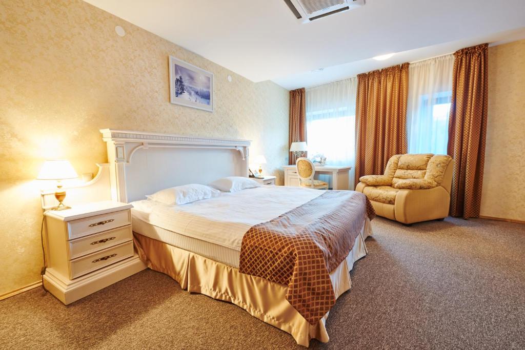 明斯克明斯克维多利亚扎姆科沃伊酒店的一间卧室配有一张大床和一把椅子
