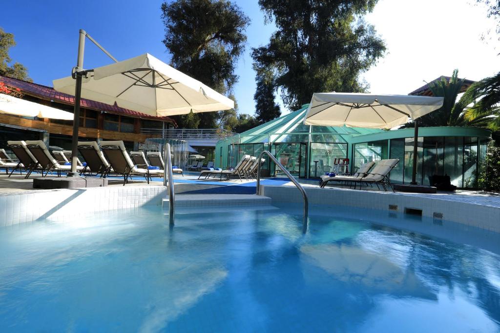 San Esteban科拉松温泉酒店的一个带两把遮阳伞和椅子的游泳池