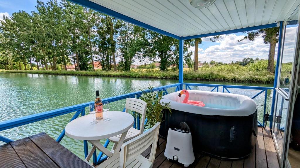 Cottage flottant terrasse gamme supérieure option jacuzzi proche Dijon的船上配有浴缸和甲板上的桌子