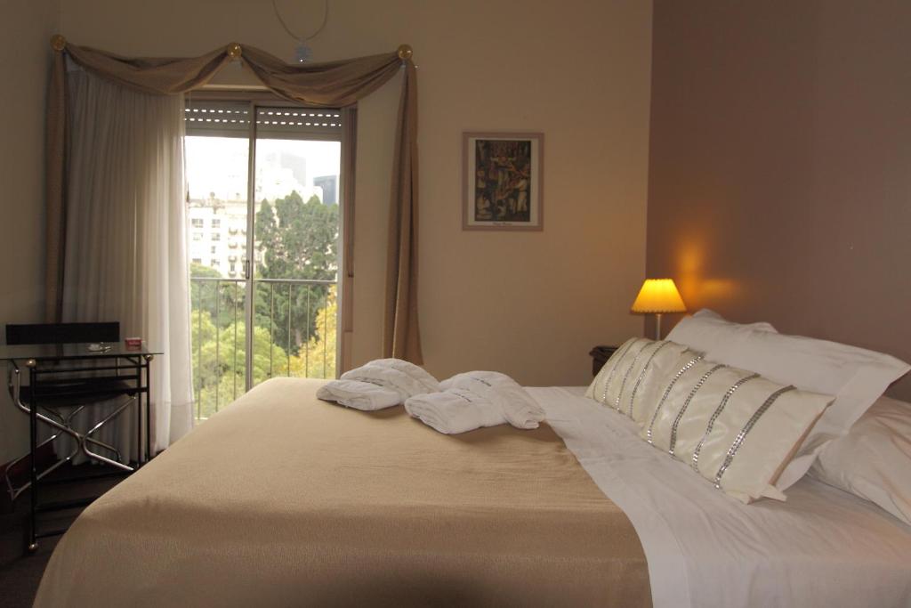 布宜诺斯艾利斯罗马广场酒店的卧室配有一张大白色床和窗户