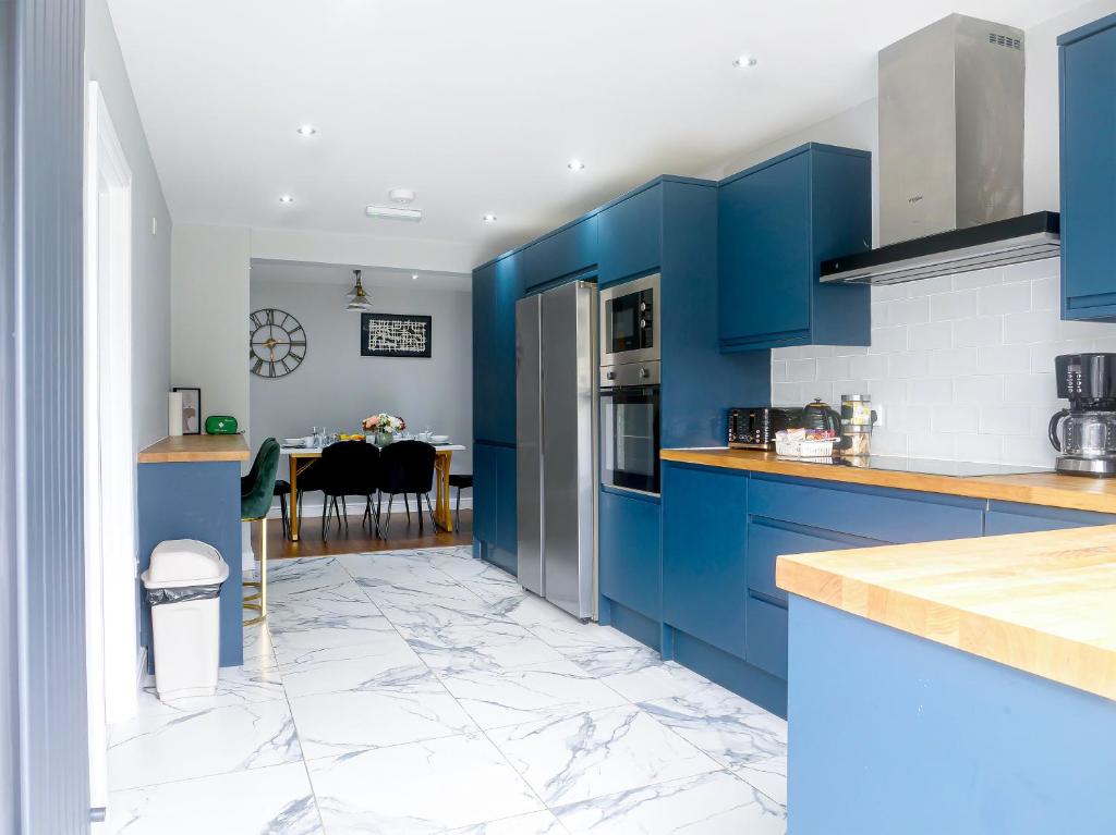 贝克斯利黑思Royal Luxe 6 Bed House in London的一间设有蓝色橱柜的厨房和一间用餐室