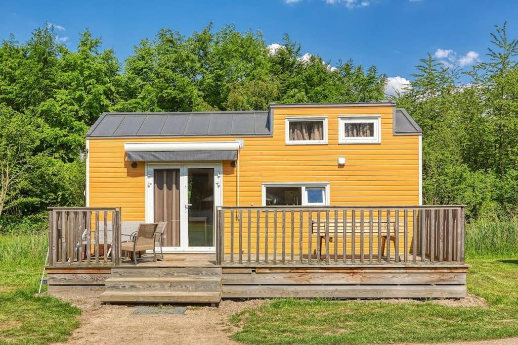 泽沃德Yellow Tiny House with shared pool的一座黄色的小房子,设有木甲板