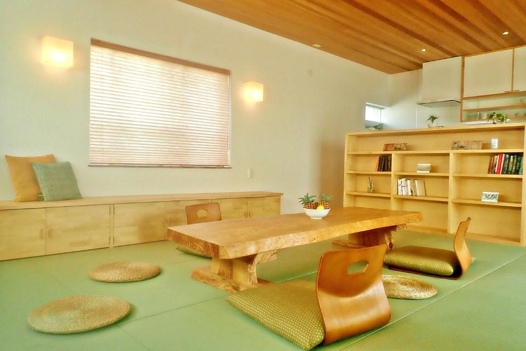 石垣岛Guest House Ishigaki的客厅配有木桌和椅子