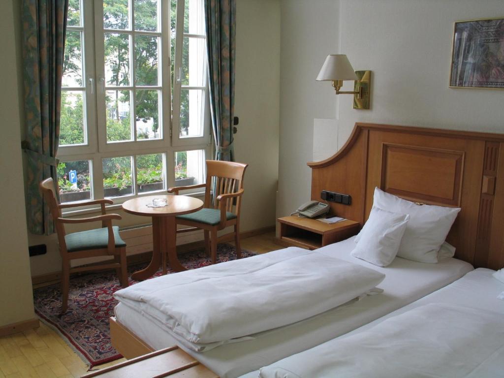 特里尔Hotel Römischer Kaiser的酒店客房设有两张床、一张桌子和一个窗户。