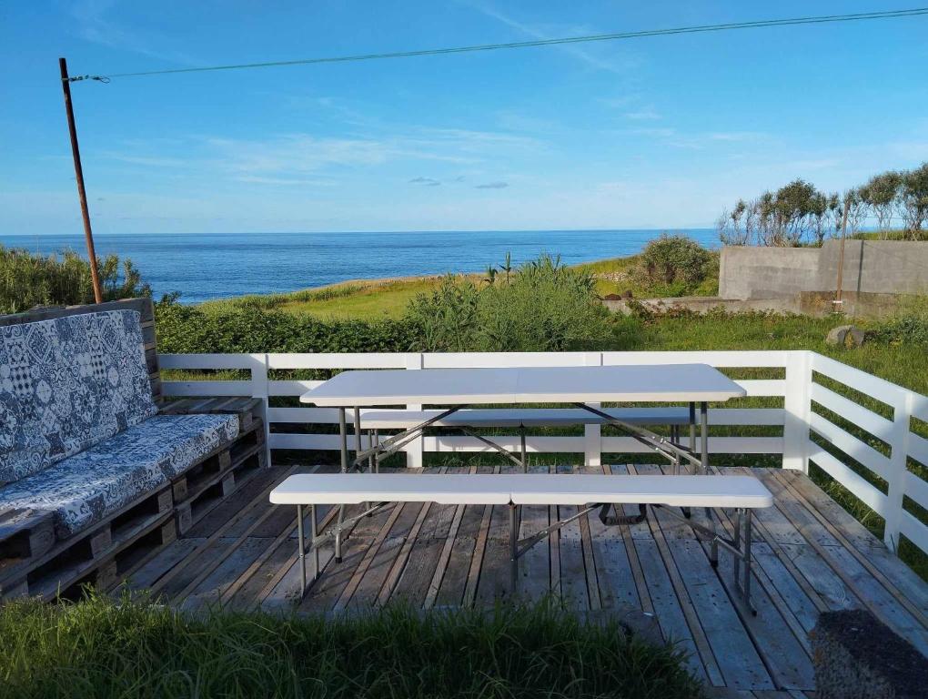 Praia da GraciosaCasa dos Fenais的野餐桌和海洋甲板上的长凳