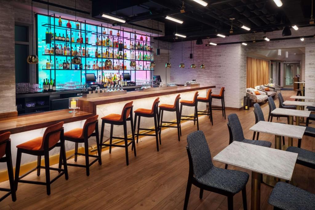 纽约Hampton Inn by Hilton New York Times Square的餐厅内的酒吧配有木桌和椅子