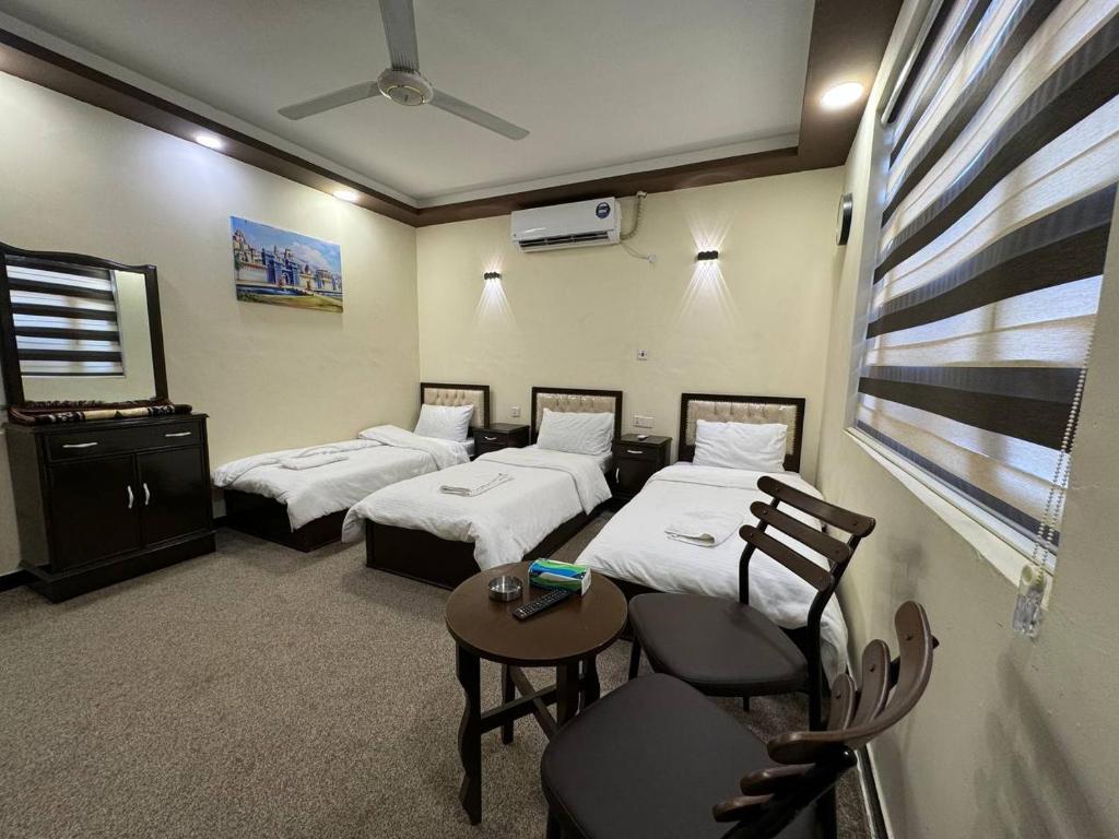 巴格达SAFIR BAGHDAD HoTEL的带三张床和桌椅的房间
