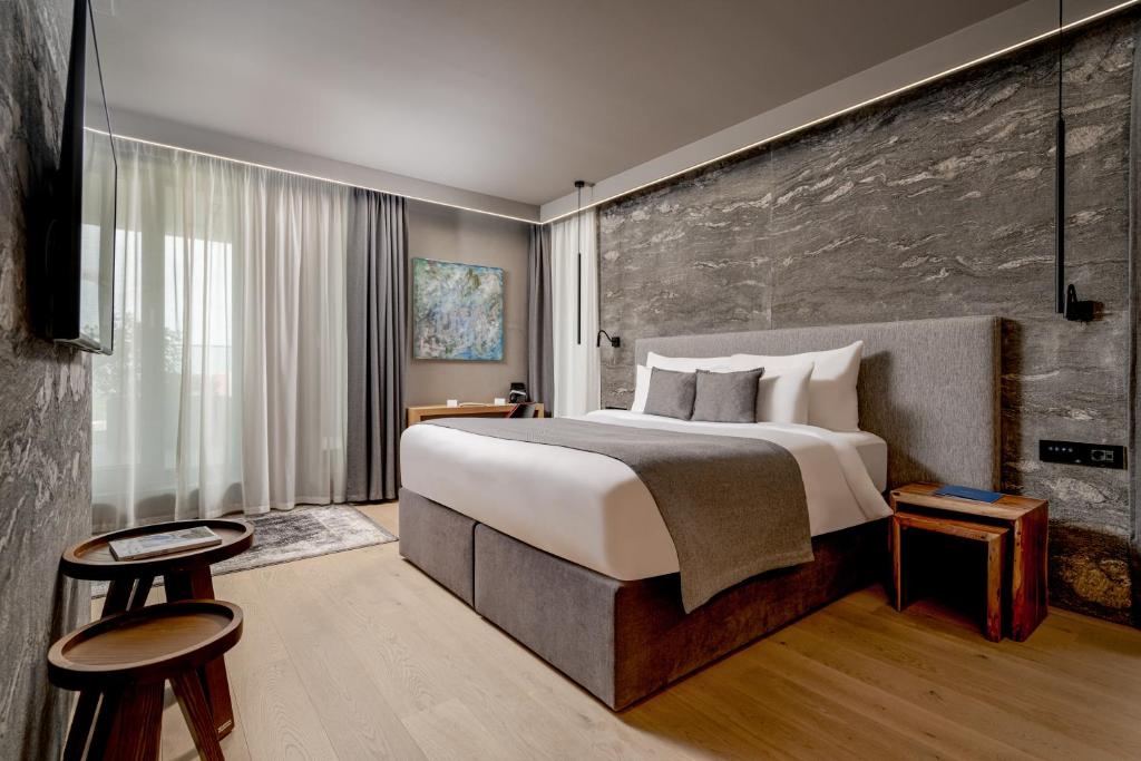 布拉索夫Qosmo Brasov Hotel的酒店客房设有一张大床和两张凳子