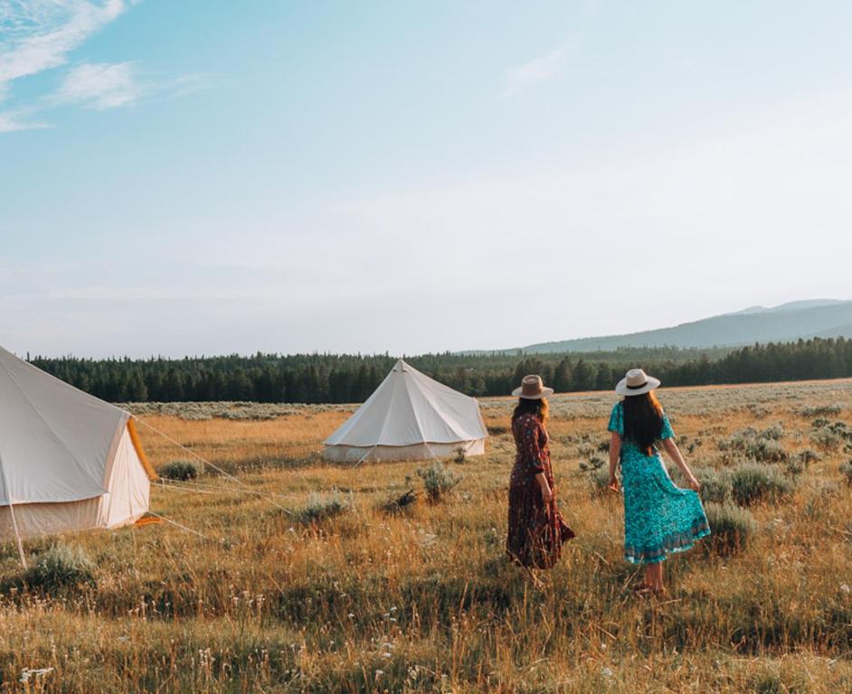 艾兰帕克Yellowstone Glamping的两名妇女在帐篷旁边的田野里散步