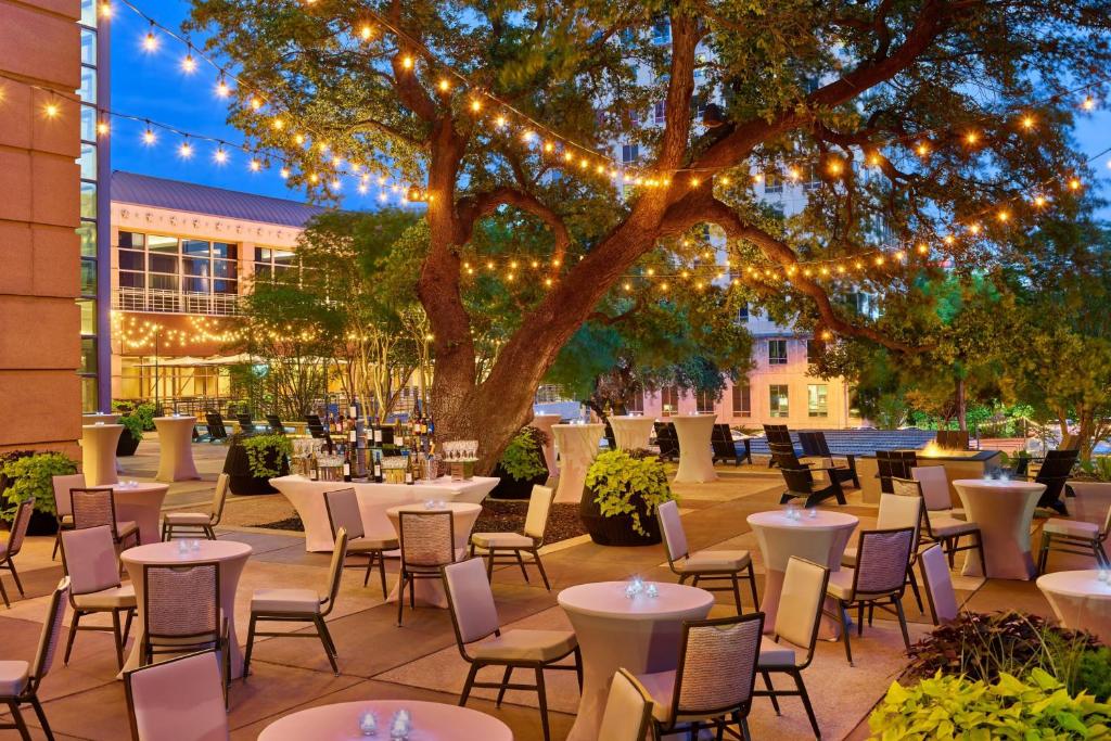 奥斯汀Downright Austin, A Renaissance Hotel - New Hotel的树下带桌椅的天井,灯光