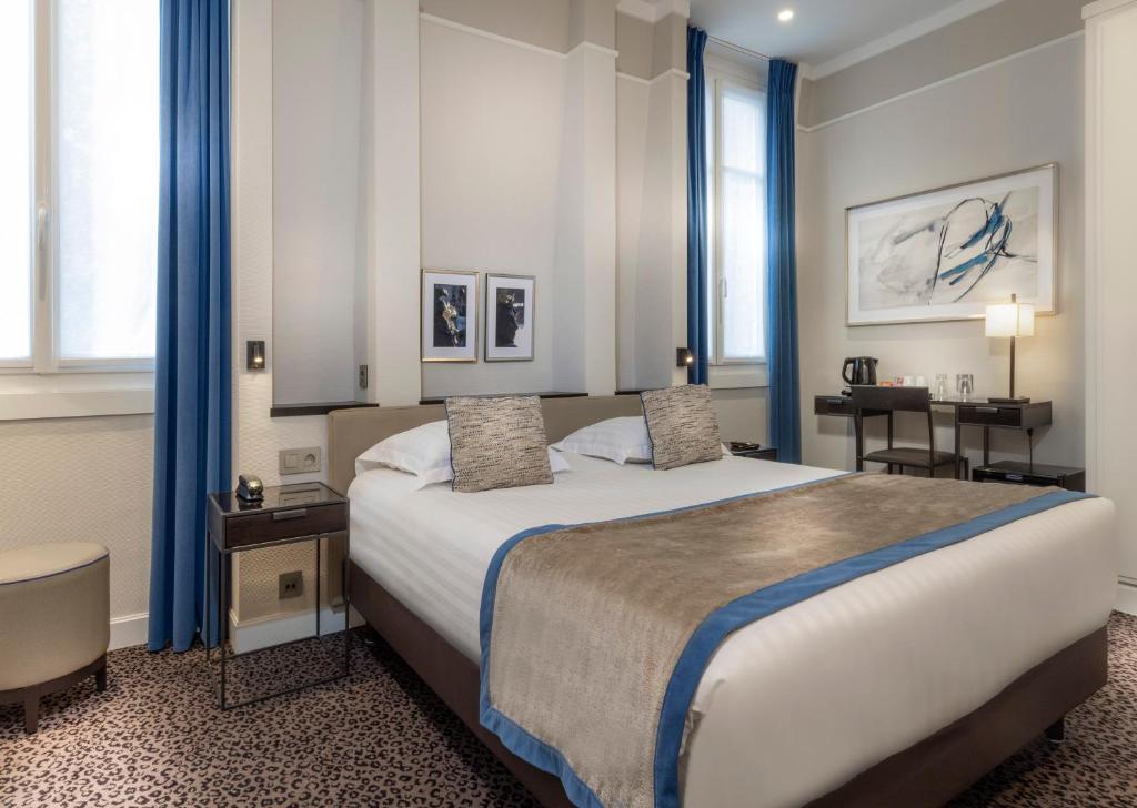 巴黎树林香榭丽舍酒店的一间卧室配有一张带蓝色窗帘的大床