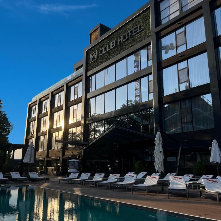 敖德萨M1 Club Hotel的一座带椅子的建筑,前面有一个游泳池